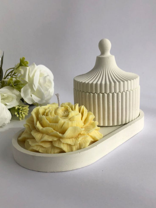decorative candle set with a flower-shaped candle and an elegant ribbed container with lid, placed on a tray