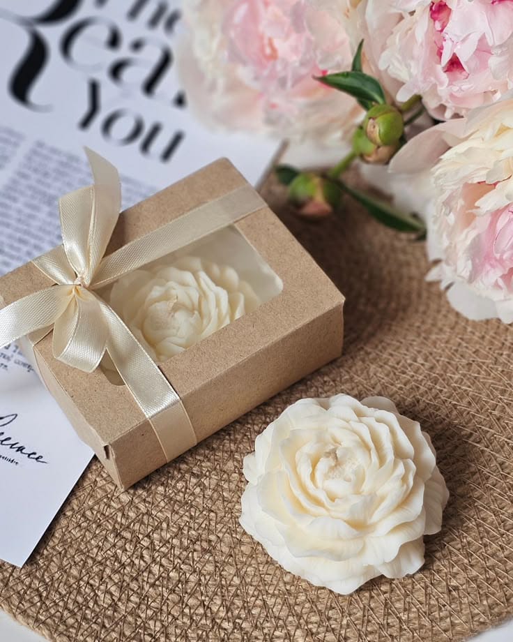 decorative candle set with a flower-shaped candle and an elegant ribbed container with lid, placed on a tray